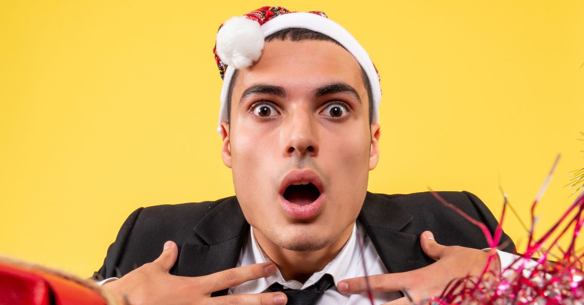 A young man in a Santa hat with a surprised expression, perfect for a funny animal joke reaction.