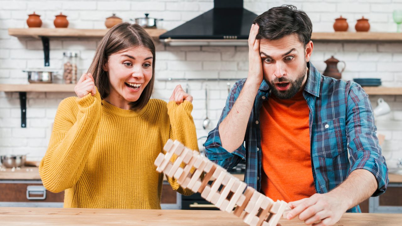 A man and woman reacting with excitement and surprise while playing a block stacking game, enjoying the Ultimate Brain Teaser Challenge: Fun Mind Games to Try!