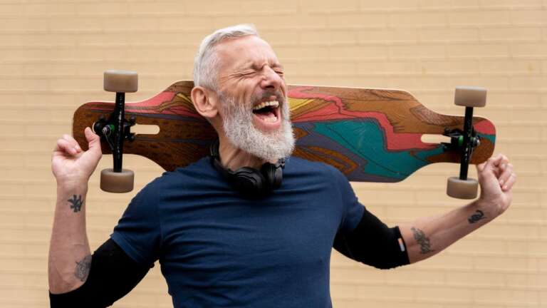 A grandpa with a big beard, laughing joyfully while holding a skateboard over his shoulder. Classic Dad Jokes That Never Get Old