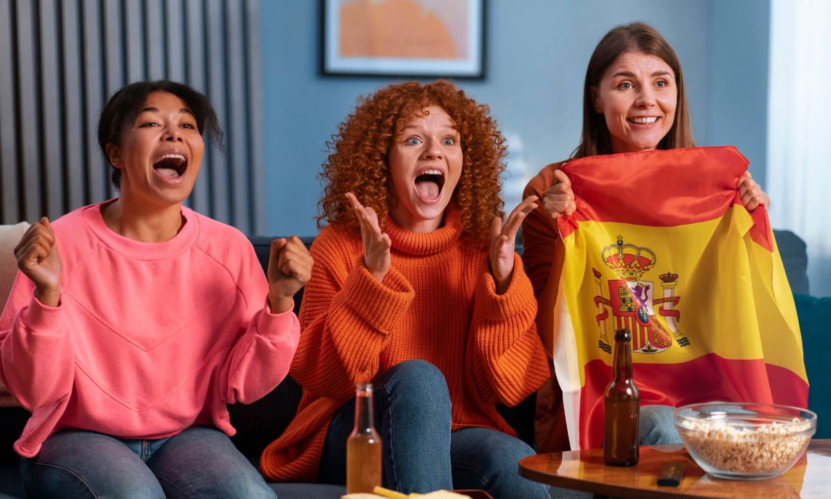 Excited female football fans watching match, cheering for Spain and sharing funny jokes for friends and family.