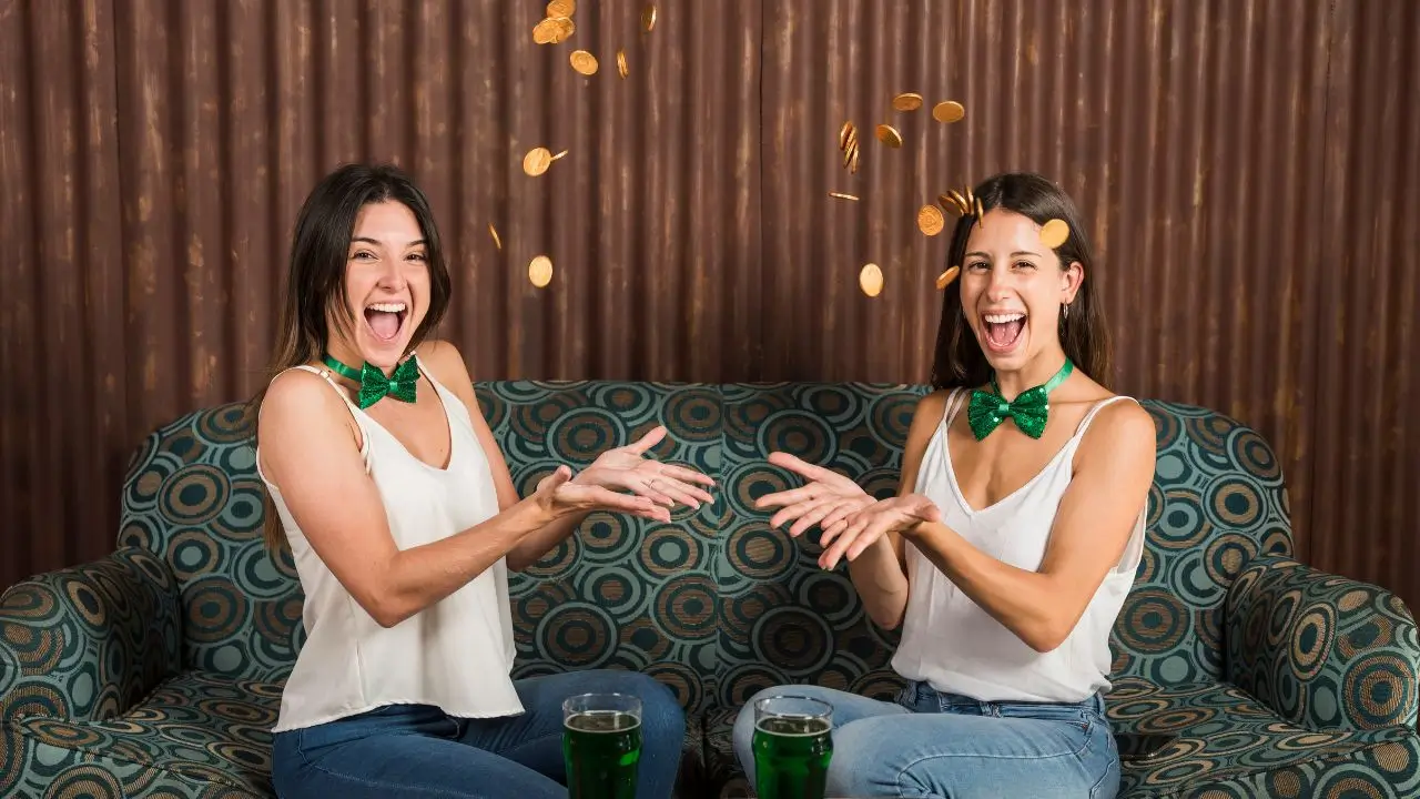 Two happy young women laughing and throwing coins in the air while celebrating together, representing the fun of 50+ Funny Knock-Knock Jokes That’ll Make You Laugh Out Loud.