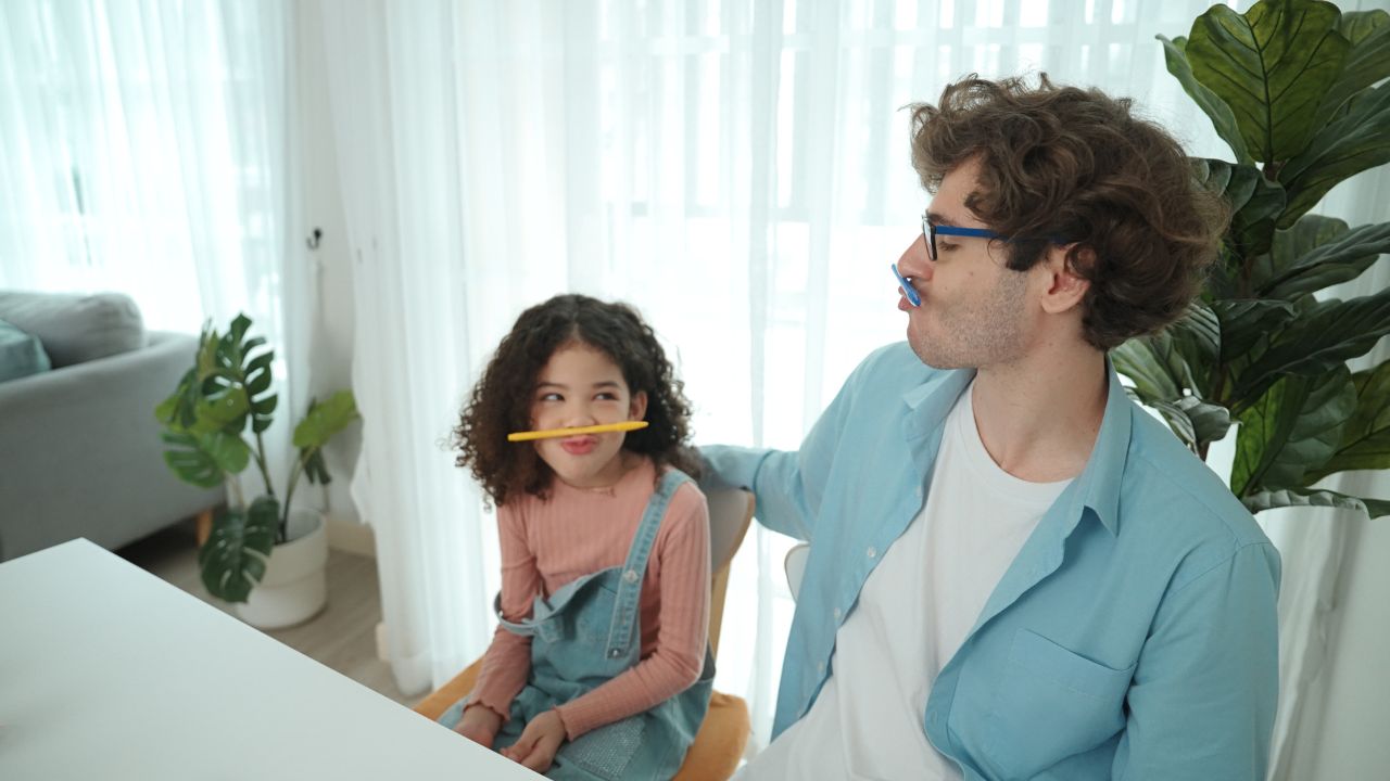 A dad and daughter are playfully posing with pencils on their faces, having fun togethe. Family-Friendly Dad Jokes That Bring Everyone Together