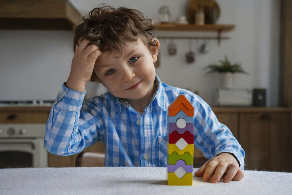 A smiling boy in a blue checkered shirt playing a memory game, symbolizing fun learning and easy brain teasers for kids.