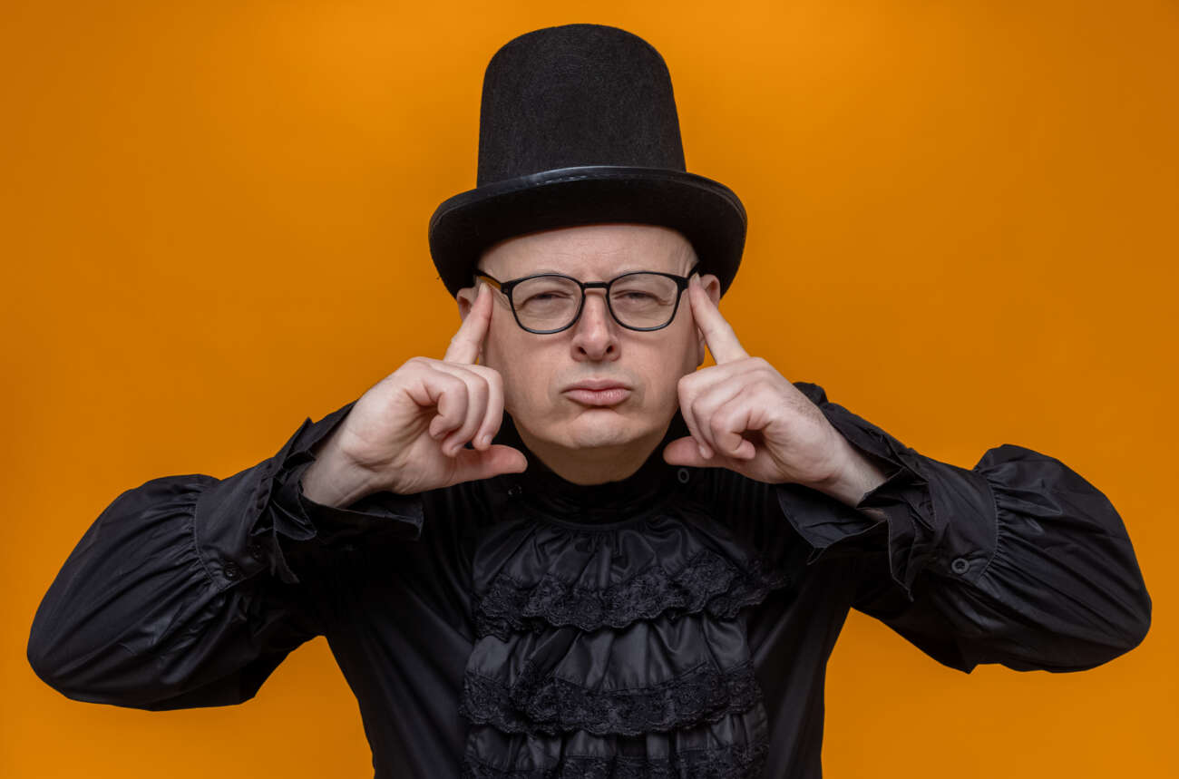A thoughtful man wearing a black top hat and glasses focuses deeply, symbolizing mental effort and concentration for brain teasers.