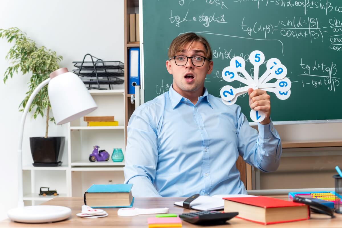 Surprised teacher holding number cards in front of a blackboard – Riddle Me Smart: Best Brain Teasers with a Twist.