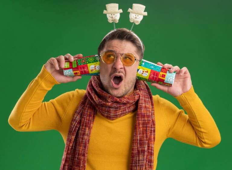 "A man in a yellow sweater and scarf with funny holiday accessories, holding colorful Christmas crackers with a silly expression, ready for laughs." Short & Sweet Funny Jokes for Quick Giggles"