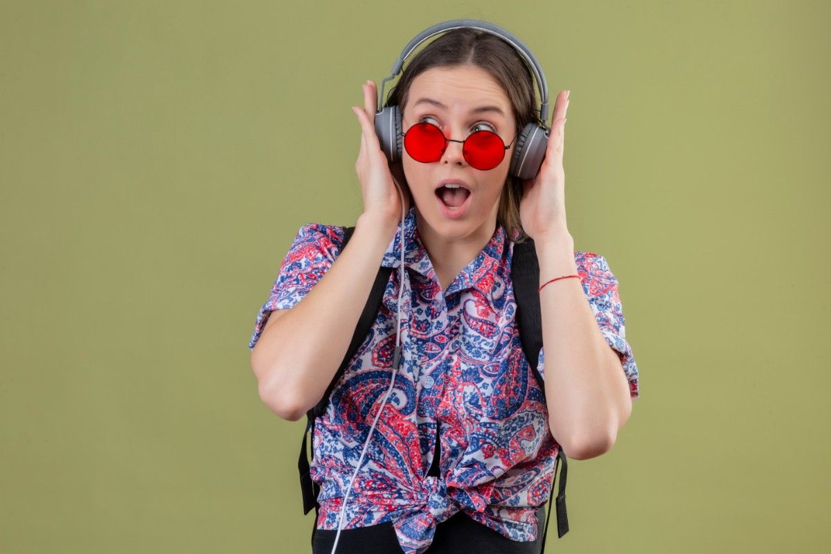 Surprised woman in red sunglasses and headphones, expressing excitement while listening to music. Family-Friendly Knock-Knock Jokes: