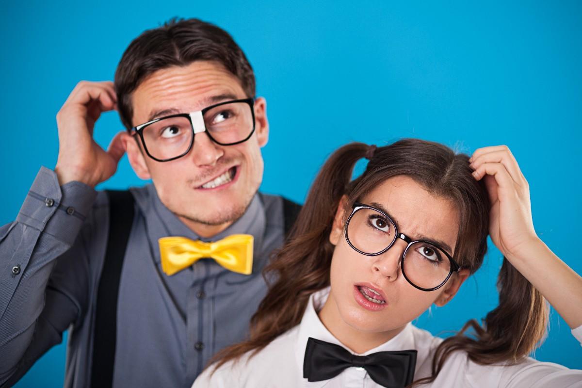 A confused man and woman wearing big glasses and bow ties, scratching their heads with funny expressions.