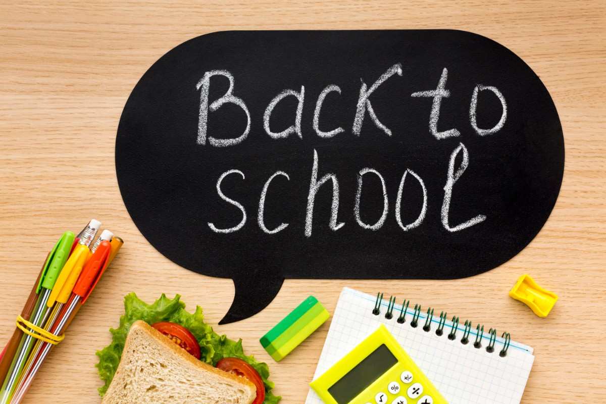 A flat lay image of school essentials including a sandwich, calculator, pens, and a notebook with "Back to school" written on a blackboard. Funny School Jokes That’ll Make You Miss Class (Almost!) 