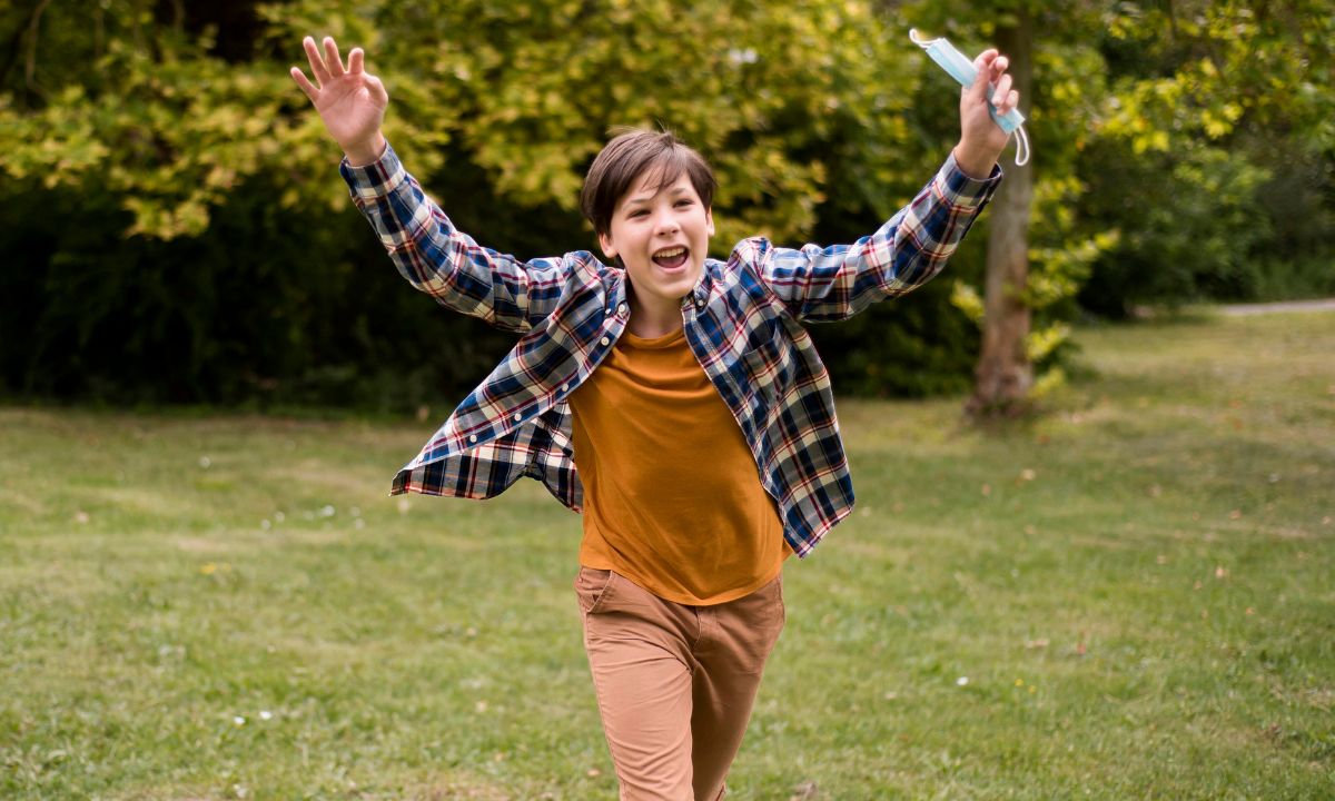 Excited boy running on grass with a big smile. Kid Jokes to Brighten Up Your Day