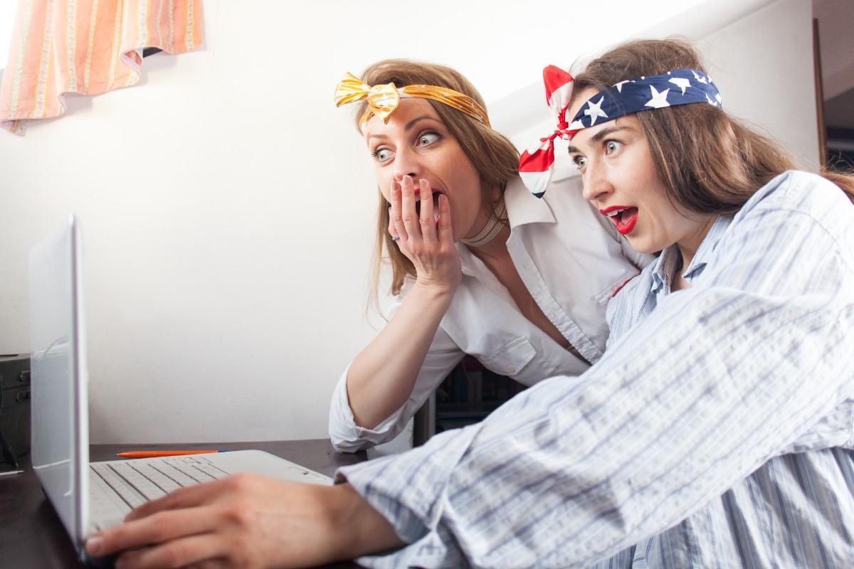Two women react in shock while watching something on a laptop, with their hands on their faces in disbelief. Kid-Friendly Funny Jokes You Can’t Read Without Laughing – The Surprising Reactions to Great Jokes.